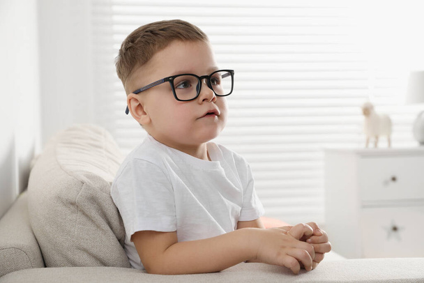 Cute little boy in glasses on sofa at home. Space for text - Фото, зображення