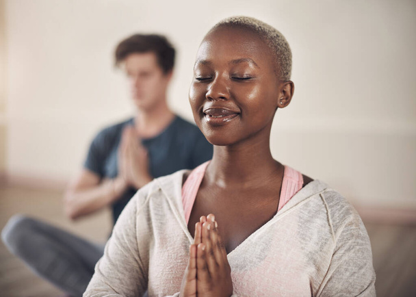 Медитацией я освобождаю негатив. привлекательная молодая женщина сидит и медитирует после занятий йогой в помещении - Фото, изображение