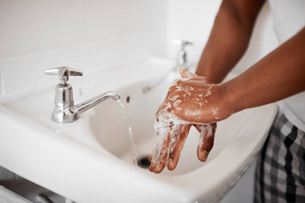 Clean, hygiene and person washing hands in the bathroom with soap for wellness, health and bacteria prevention. Protection, home and man cleaning hand with water in his apartment as morning routine. - Fotó, kép