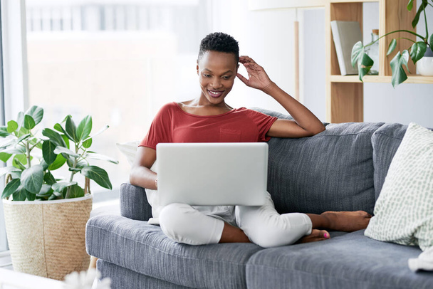 Vrolijke, zwarte vrouw en ontspannen met laptop op een bank, comfortabel en koel in het weekend. Streamen, glimlachen en Afrikaanse vrouwelijke persoon online voor internet, zoeken en inschrijven in een woonkamer. - Foto, afbeelding