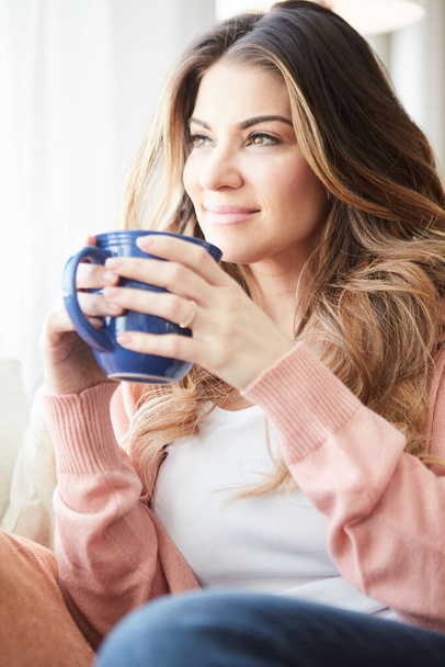 Theres more to life than just being busy all the time. a beautiful young woman having coffee while relaxing at home - Photo, image