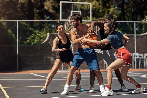 Баскетбол - это быстрое реагирование. группа спортивных молодых людей, играющих в баскетбол на спортивной площадке - Фото, изображение
