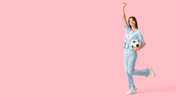 Boldog fiatal nő focilabdával rózsaszín háttér hely szöveges - Fotó, kép