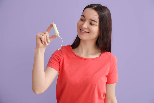 Young woman with tampon on lilac background - Photo, Image