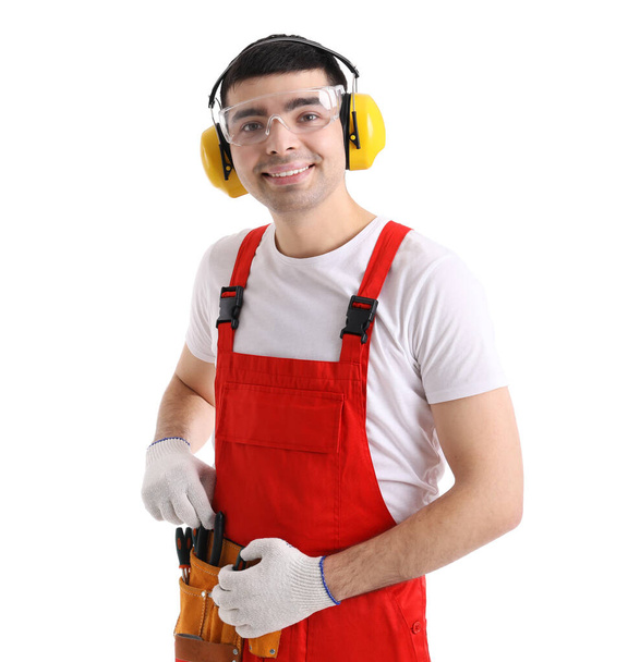 Jovem carpinteiro em protetores auditivos com saco de ferramentas em fundo branco - Foto, Imagem