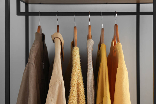 Rack with stylish clothes near light wall, closeup - Photo, Image
