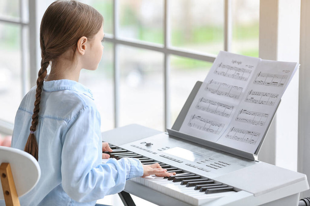 Маленька дівчинка грає синтезатор вдома
 - Фото, зображення