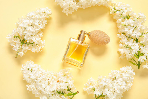 Πλαίσιο κατασκευασμένο με όμορφα λιλά λουλούδια και μπουκάλι άρωμα σε ανοιχτό κίτρινο φόντο - Φωτογραφία, εικόνα