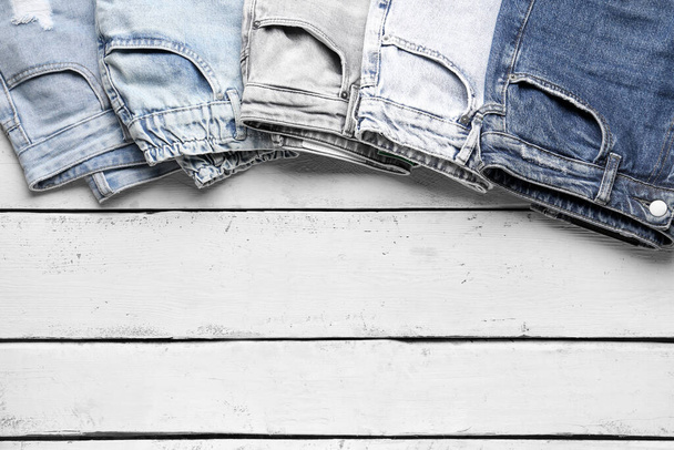 Different stylish denim jeans on wooden background, closeup - Photo, Image