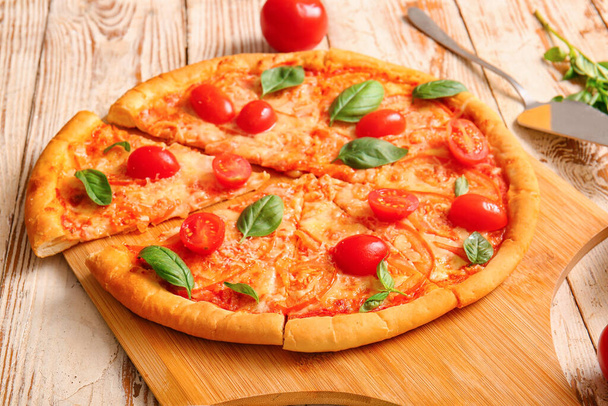 Deska ze smaczną pizzą margarita na białym drewnianym tle - Zdjęcie, obraz