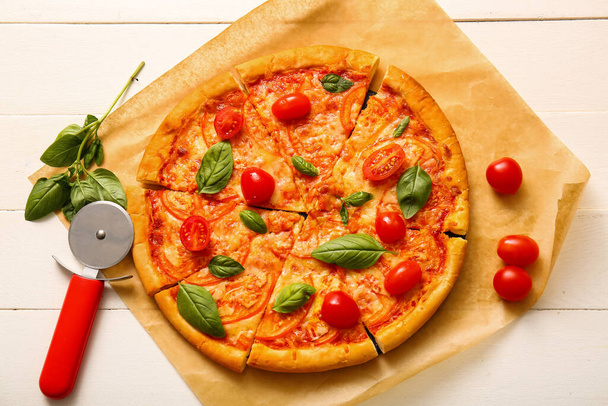 Papier do pieczenia z smaczną pizzą margarita na białym drewnianym tle - Zdjęcie, obraz