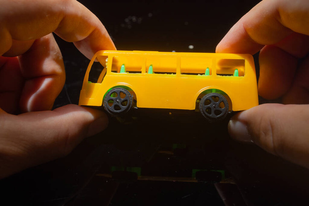  ChatGPT A man holds a plastic model of a yellow school bus, showcasing a nostalgic representation of childhood and transportation. yellow school bus plastic toy model in hands of men. High qualit - Photo, Image