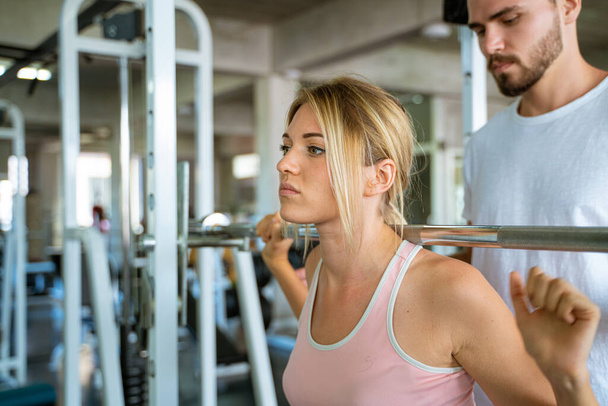 Sport man trainning woman exercise lifting weight in sport gym fitness gym - Foto, imagen
