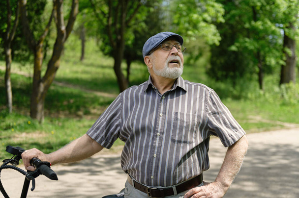Позитивный, харизматичный пожилой человек на эко скутере вышел на прогулку в парк. Здоровый образ жизни пожилых людей. - Фото, изображение