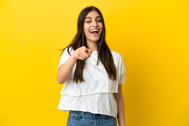 Young caucasian woman isolated on yellow background surprised and pointing front - Photo, Image