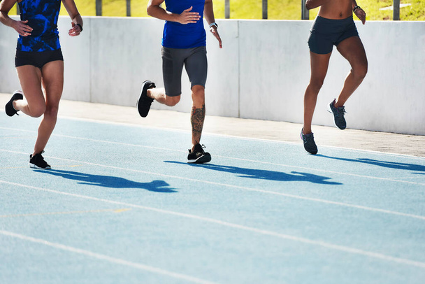 People, legs and running on stadium track for athletics, fitness or exercise in training outdoors. Leg of athlete group in sports run competition, exercising or workout for healthy cardio wellness. - Foto, Imagen