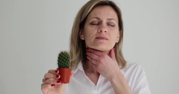 Mujer sosteniendo cactus en la mano sugiriendo dolor de garganta. Dolor de garganta causa diagnóstico y tratamiento - Imágenes, Vídeo