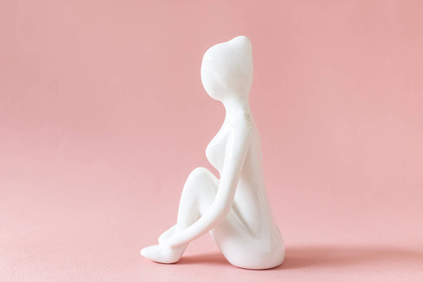 Figurine de yoga en céramique de femme faisant pose de yoga sur fond rose - Photo, image