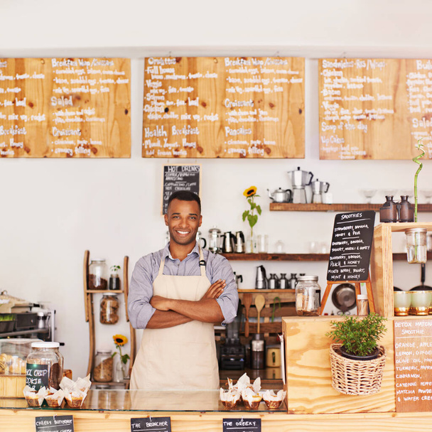 Portret, zwarte man en ober met armen gekruist in café met trots voor carrière of werk. Barista, glimlach en vertrouwen van Afrikaan uit Nigeria als restauranteigenaar, kleine zaak en coffeeshop. - Foto, afbeelding