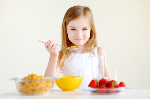 Little girl eating cereal with strawberries - Фото, изображение