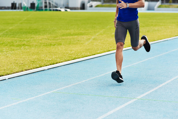 Man, legs and running on stadium track for fitness, workout or exercise of athlete training outside. Leg of male person or runner exercising in run, athletics or sports competition for healthy cardio. - Photo, Image