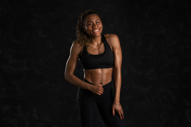 Confident sporty young black African woman, against black background. - Photo, image