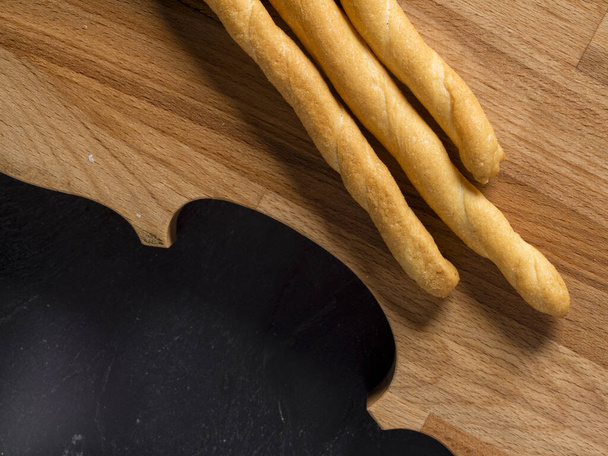mixed grain Italian golden baked breadsticks grissini overhead studio isolated shot on wooden board on black background. - 写真・画像