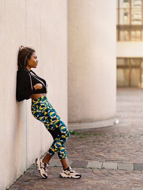 Young black african sporty woman full body portrait outdoors against a wall in a sunny day. Lifestyle. - Zdjęcie, obraz