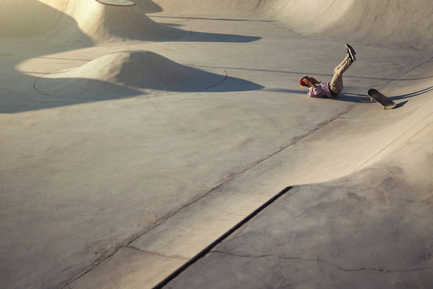 Skateboarder portrait falling down at skate park. Sunset light, life style. - Photo, Image