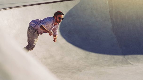 Skateboarder portrait sliding at skate park. Sunset light, life style. - Фото, изображение