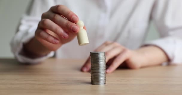 Person puts figurine of human growing coins. Wealth, savings and wealth concept - Footage, Video