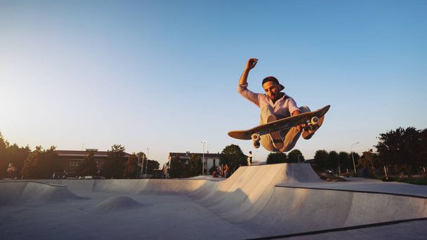 Skateboarder portrait jumping at skate park. Sunset light, life style. - 写真・画像