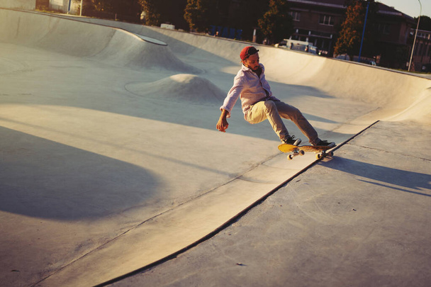 Skateboarder portrait sliding at skate park. Sunset light, life style. - Fotó, kép