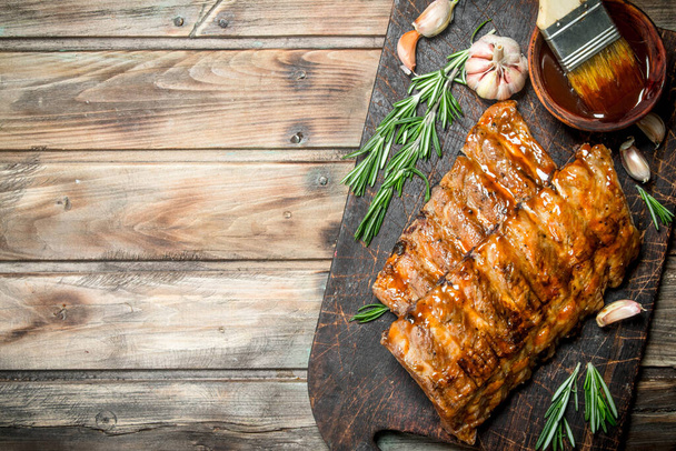 Grilled ribs with rosemary, spices and sauce. On a wooden background. - Fotografie, Obrázek