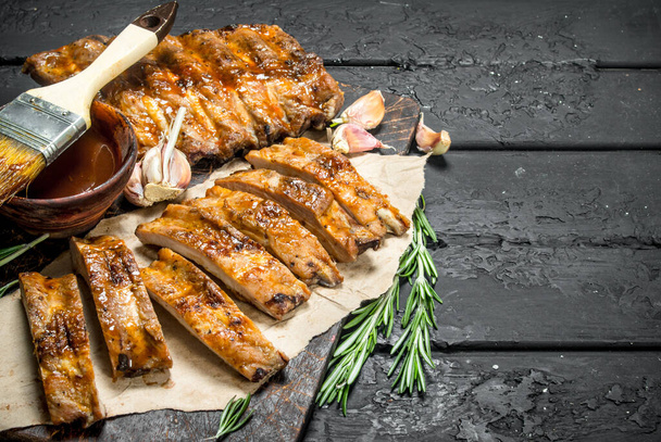 Sliced grilled ribs with sauce. On a black rustic background. - Photo, Image