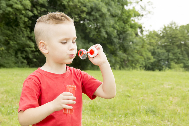 мальчик надувает воздушный шар, гуляя в парке
 - Фото, изображение
