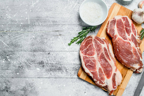Raw pork steaks with salt. On a rustic background. - Photo, Image