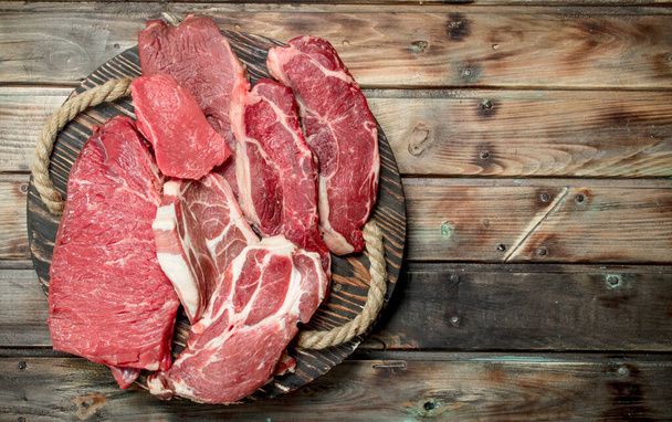 Raw meat. Beef and pork steaks on the Board. On a wooden background. - Foto, imagen