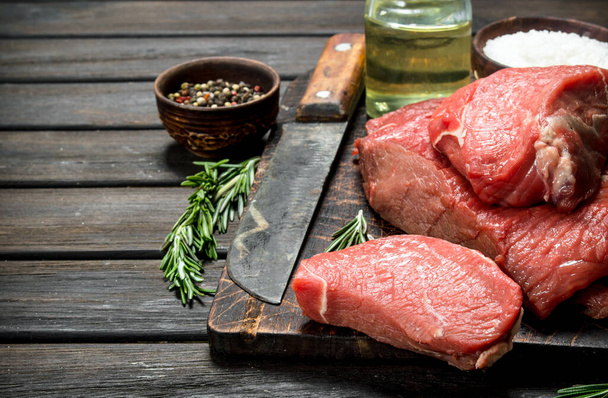 Raw meat. Fresh beef with spices and an old knife. On a wooden background. - Foto, afbeelding