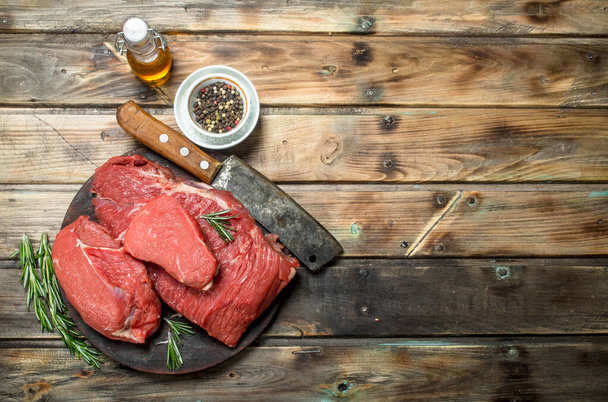 Raw meat. Fresh beef on a cutting Board with herbs and spices. On a wooden background. - Foto, afbeelding