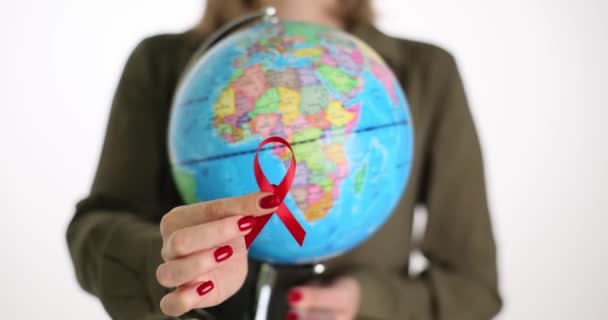 Closeup of globe with red ribbon for fight against AIDS in female hands. Epidemiology of HIV infection in world - Footage, Video