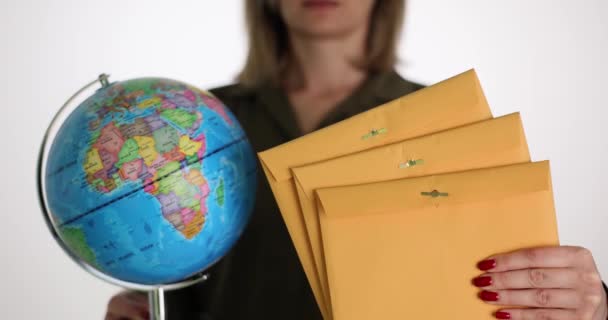 Enveloppe postale jaune avec globe dans les mains des femmes. Journée mondiale de la poste et service de messagerie international - Séquence, vidéo