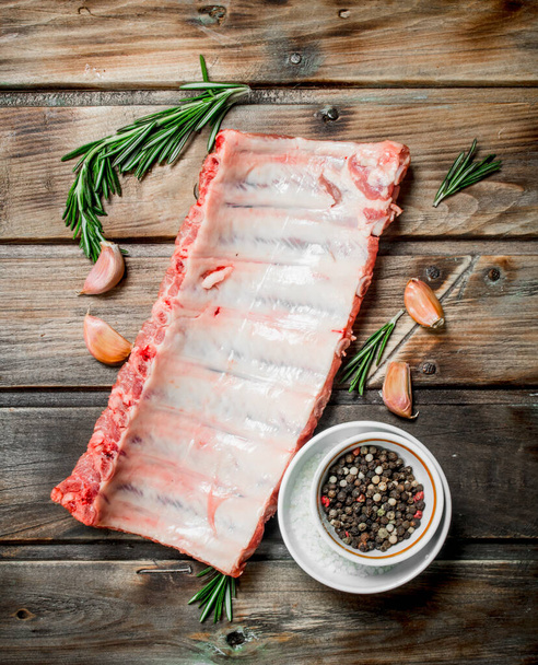 Raw ribs with spices and herbs . On a wooden background. - Фото, зображення