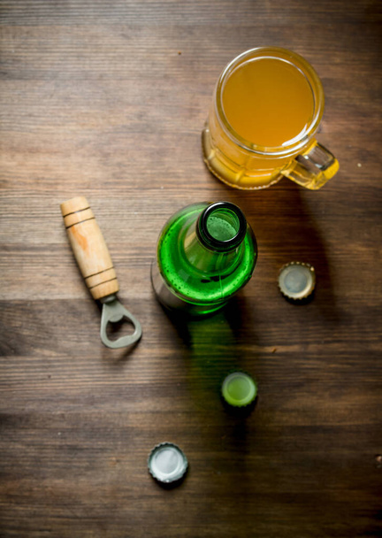 Beer in a glass mug and a bottle. On wooden background - Photo, image