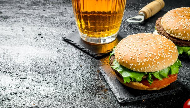 Burgers and beer in a glass. On black rustic background - Valokuva, kuva