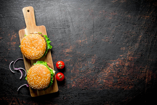 Burgers with beef and onion slices. On dark rustic background - Φωτογραφία, εικόνα