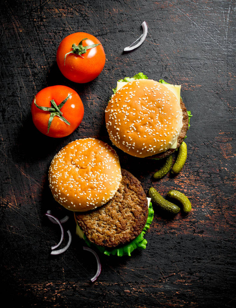 Burgers with gherkins and tomatoes. On dark rustic background - Foto, Imagem