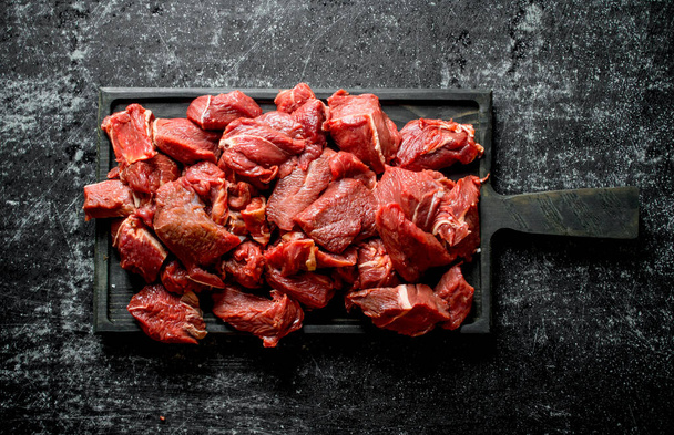 Sliced raw beef on a black cutting Board. On black rustic background - Photo, Image