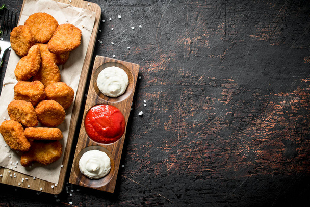 Chicken nuggets and different sauces. On dark rustic background - Фото, зображення