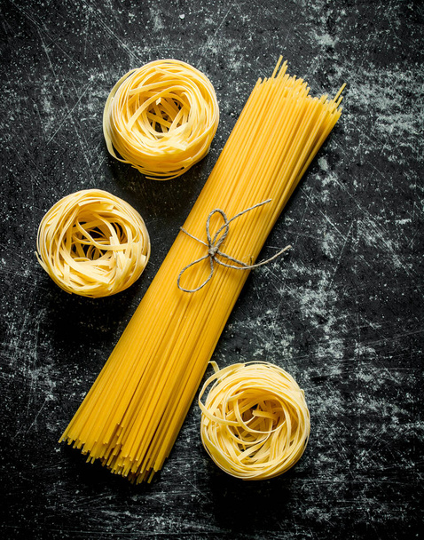 Tagliatelle and spaghetti raw. On black rustic background - Photo, Image